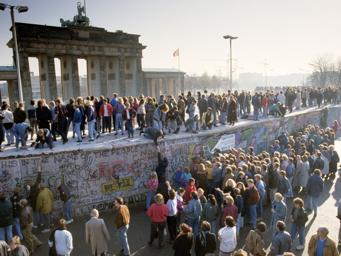 Fall of the Berlin Wall: people from East and West Berlin climbing on the Wall at the Brandenburg Gate, Berlin, Germany